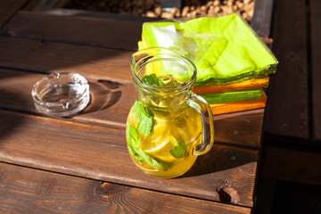 A carafe with lemonade. A jar of water with mint. No alcoholic drink at a party. Healthy drink with vitamin C. Filming in natural light.