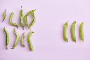 Ugly homegrown pea with a normal pea on a pink background. copy space.