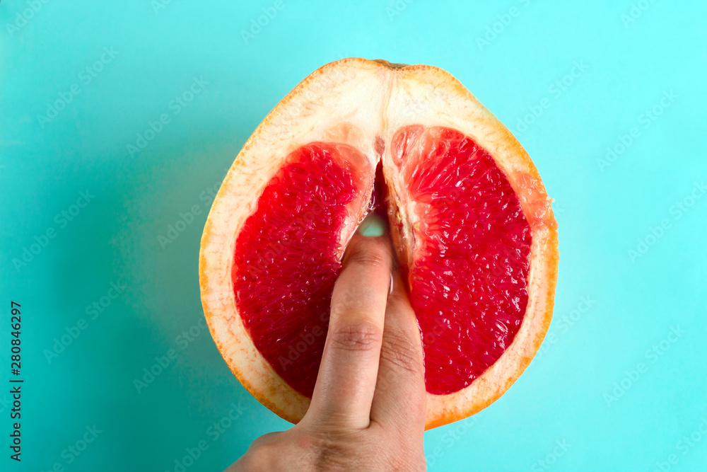 two fingers in a grapefruit isolated on a blue background top view sex concept - obrazy, fototapety, plakaty 
