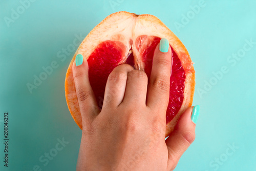 Fotografie, Tablou  two fingers in a grapefruit isolated on a blue background top view sex concept