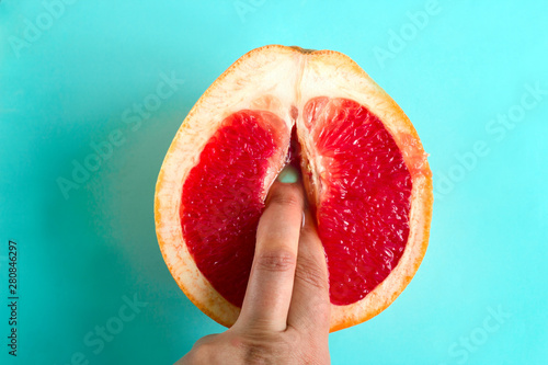 Cuadros en Lienzo two fingers in a grapefruit isolated on a blue background top view sex concept