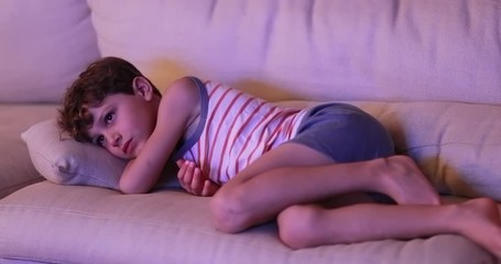 Wall Mural - Small boy on the couch watching TV at night in the living room