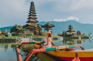 beautiful girl kayaking on the catamaran at the ulun datu pura bratan temple, in bali