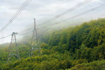 high voltage power lines tower in mountains.  energy delivery background. efficient electricity delivery concept. hazy weather with overcast sky