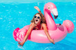 © Тарас Нагирняк - Blonde girl  resting  in the  summer pool on an inflatable pink flamingo in a bathing suit.