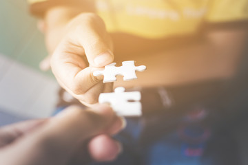 Hand of two people holding jigsaw puzzle connecting together. Concept of partnership and teamwork in business strategy