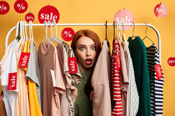surprised girl hiding among clothes on hangers woman is being surprised after hearing the prizes of 