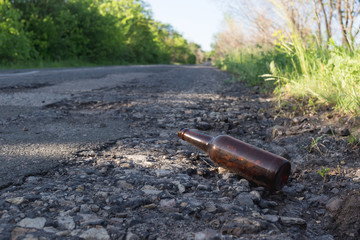 Brown beer bottle by the road.