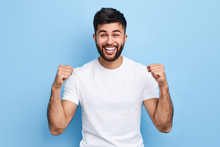 Excited Arab Man Celebrating Success With Two Fists In Air Isolated On The Blue Background. Close Up Portrait, Studio Shot , Happiness, Positive Emotion And Feeling. I've Done It. Facial Expression