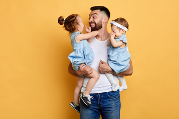 Young happy father holding his his little daughters in hands isolated yellow background. close up photo.feeling, emotion, fatherhood