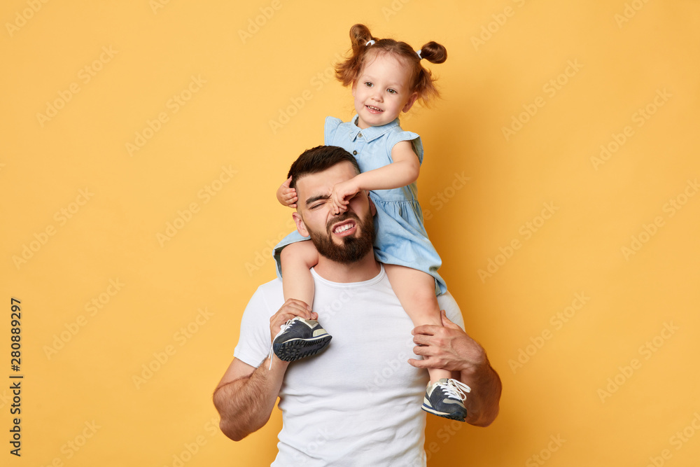 naughty girl holding her daddy's nose, display negative, angry behaviour. close up photo. isolated yellow background.father cannot manage with naughty behaviour - obrazy, fototapety, plakaty 