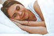 © rogerphoto - Beautiful young and happy woman sleeping while lying in bed comfortably and blissfully smiling
