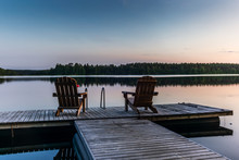 Two Wooden Chairs At Sunset On A Pier On The Shores Of The Calm Saimaa Lakein Finland - 3
