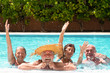 © luciano - Four senior people friends laughing enjoying the swimming pool together. Bright sunlight and transparent water. Large smiles and happiness. Floating in the water