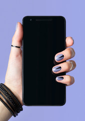 female hand with fashionable manicure holding black cell phone