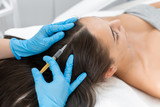 Fototapeta  - Beautician injections for healthy hair growth. Mesotherapy of the scalp. A young girl is undergoing a course of spa treatments in the office of a beautician. Moisturizing