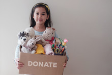 Mixed Asian Young Volunteer Girl Holding A Box Full Of Used Old Toys, Cloths, Books And Stationery For Donation, Act Of Kindness