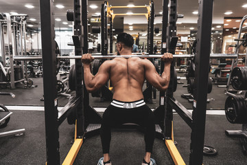 Poster - Man at the gym. Execute exercise squatting with weight, in gym