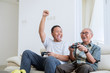© Creativa Images - Young man playing video games with his father