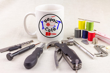 Wall Mural - Repair Cafe logo on a cup surrounded by repair tools on table top, consumer activism to repair household items to reduce waste and support a sustainable lifestyle