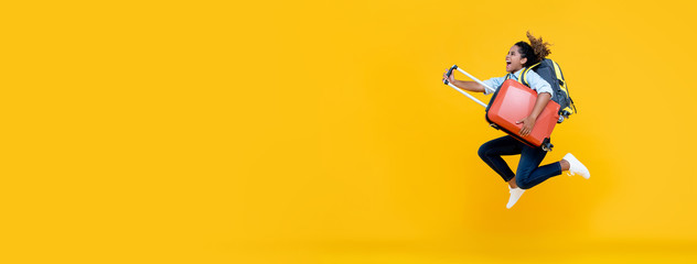 Excited African American woman tourist woman with backpack and luggage jumping