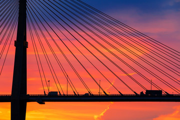 Trailer and pickup truck drives across the suspension bridge at dusk.