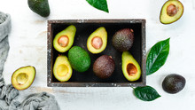 Avocado With Leaves In The Box. Rustic Style. Top View. Free Space For Your Text.