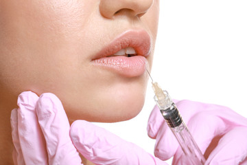 Poster - Young woman receiving injection of filler in lips on white background, closeup