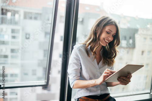 Fotografía Attractive businesswoman using a digital tablet while standing in front of windo
