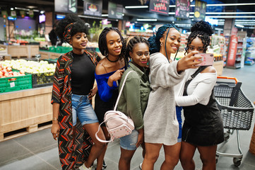 Group of five african womans making selfie by phone at supermarket.