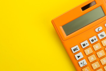 Orange calculator on a bright paper yellow background. Office supplies. Education. back to school. top view. place for text.