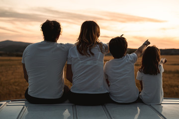 Happy family looking at the sunset in the field