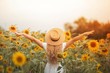 © Kristina89 - Beautiful curly young woman in a sunflower field holding a wicker hat. Portrait of a young woman in the sun. Summer.