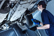 © Monstar Studio - Mechanic is repairing car at service station. Repairman is detecting problems by special software on laptop and diagnostic tool at workshop auto repair shop. Vehicle on hydraulic lift is above.