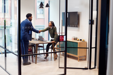 Businesswoman Shaking Hands With Male Job Candidate In Meeting Room After Interview