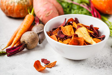 Wall Mural - Bowl of healthy vegetable chips from beets, sweet potatoes and carrots on white background.