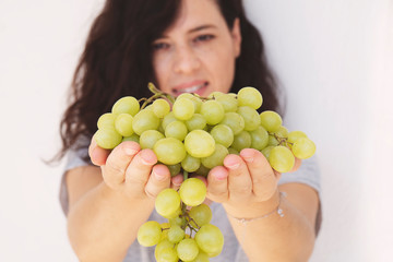 Beautiful woman, holding fresh green grape in handful, isolated on white background