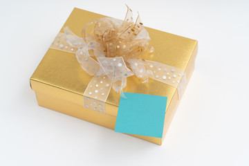 Blank adhesive note on gold gift box on white background