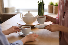 Women With Cups Of Tea At Table Near Window Indoors, Closeup