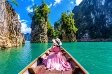 Beautiful Girl Sitting On The Boat And Looking To Mountains In Ratchaprapha Dam At Khao Sok National Park, Surat Thani Province, Thailand.