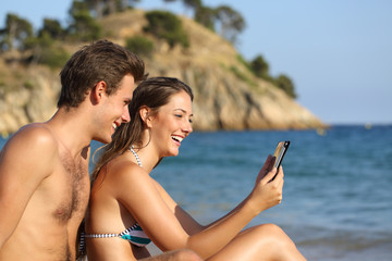 Sticker - Happy couple on the beach checking tablet