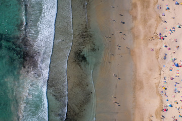  ocean waves, sandy beach with people bathing in the water, view from drone, Lanzada beach, Galicia, Spain
