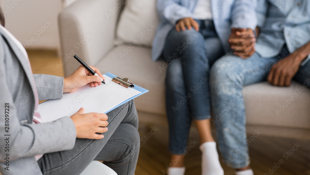 Afro couple holding hands on couch during marriage counseling session - obrazy, fototapety, plakaty 