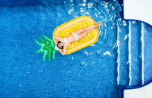 Little Girl Lying On A Pineapple-shaped Float In A Swimming Pool
