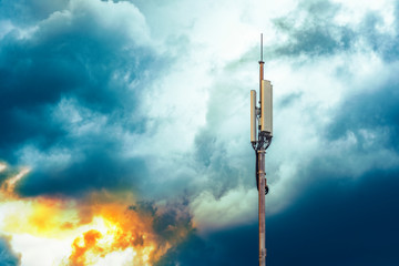 A column with transmitters and mobile telephony antennas against the sky with clouds at sunrise