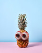 © Yaroslav Danylchenko/Stocksy - A man's face made from tropical fruits - pineapple and the eye of half of lychee with a brown bone on a duotone background.