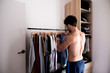 © guille Faingold/Stocksy - Shirtless man choosing clothing