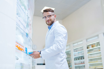 Wall Mural - Joyful brunette man working in modern pharmacy