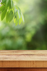 Wooden table and green leaf blurred nature background. 