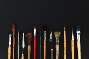 Paint brushes and mastehin on black background.